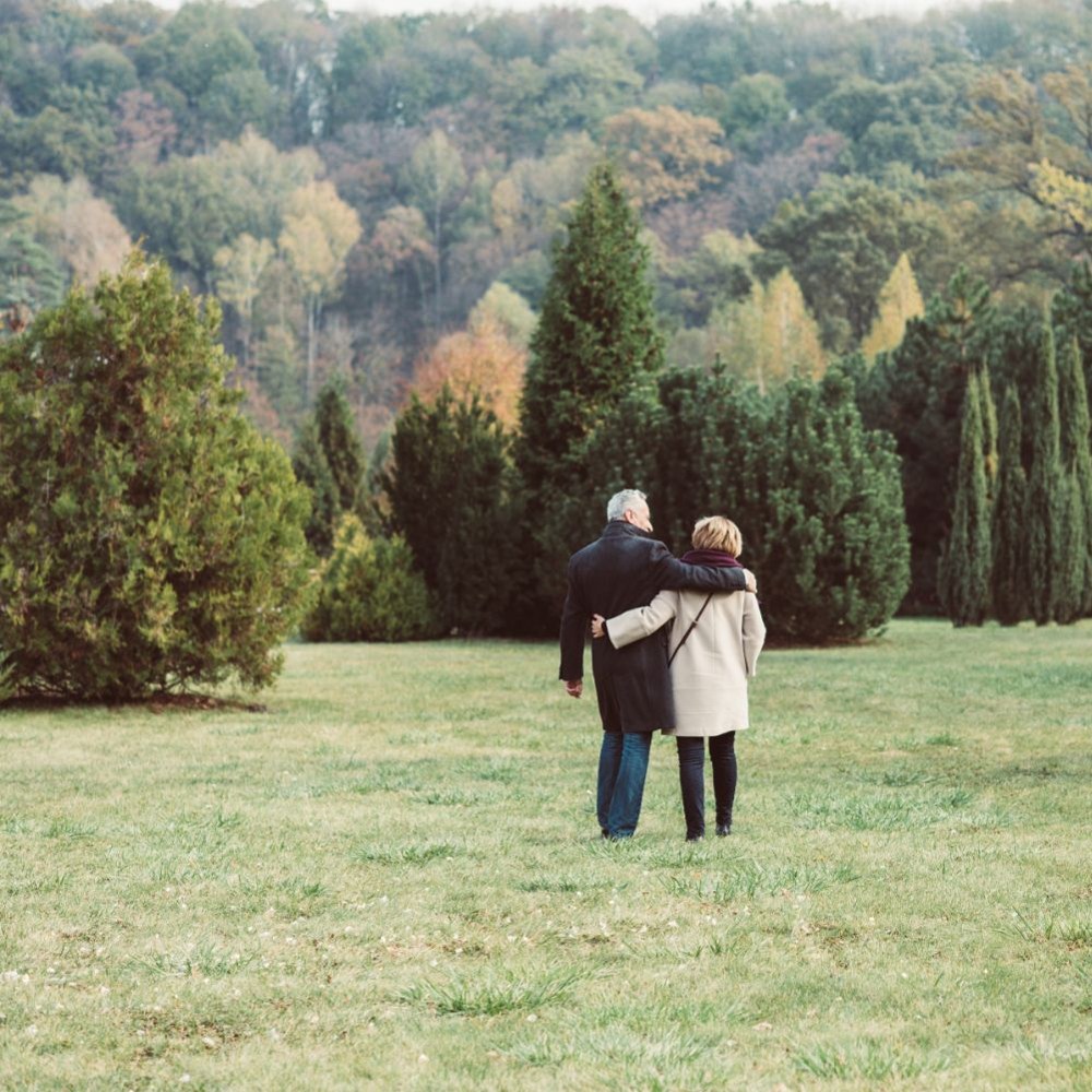 Man and woman with arms around each other walking in a meadow
