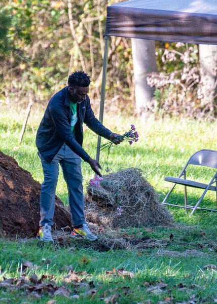 Grounds crew member dropping flowers on a burial site